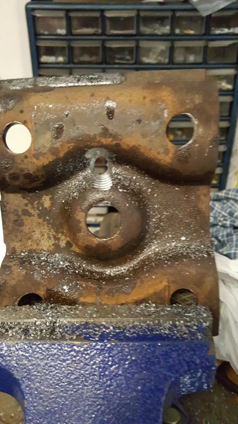 1996 Ford Bronco - A heavily rusted metal bracket is secured in a vise, showing signs of recent work and wear.