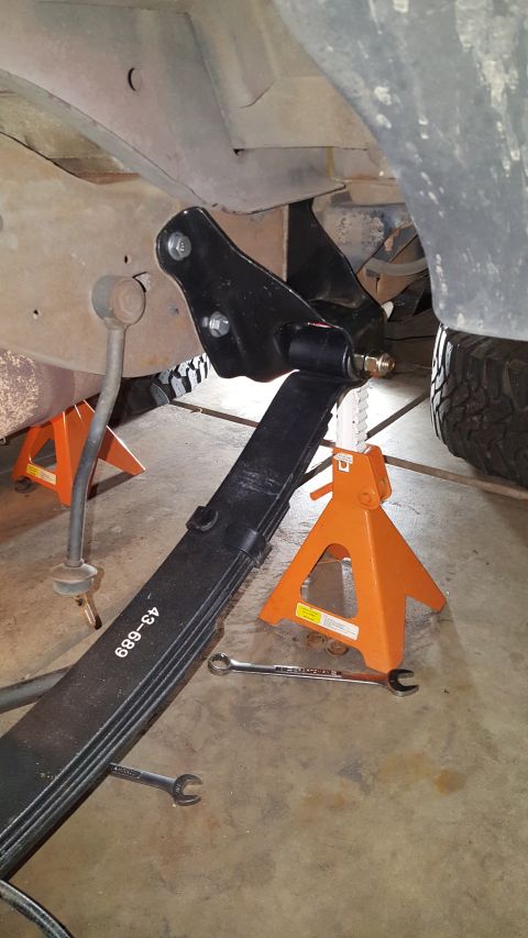 1996 Ford Bronco - Underneath view of a vehicle's suspension system during a leaf spring replacement.