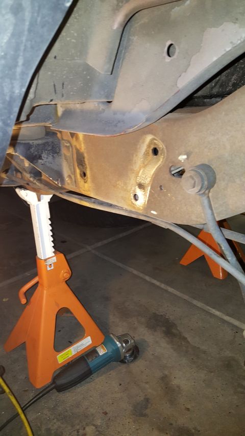 1996 Ford Bronco - Frame and suspension components are supported by jack stands, with an angle grinder nearby.