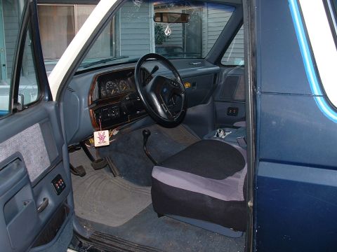 1990 Ford Bronco - The interior of the SUV features a dashboard with gauges, a steering wheel, and a driver's seat with a cover.