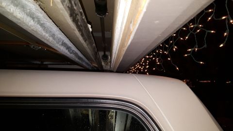 1996 Ford Bronco - The top portion of a beige SUV is visible, with Christmas lights strung above it against a dark background.