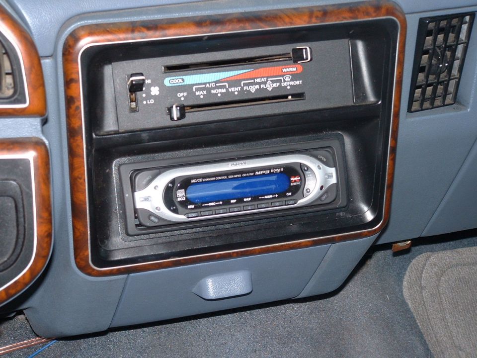 Car dashboard with wood trim, climate controls, and a Sony car stereo with a blue display