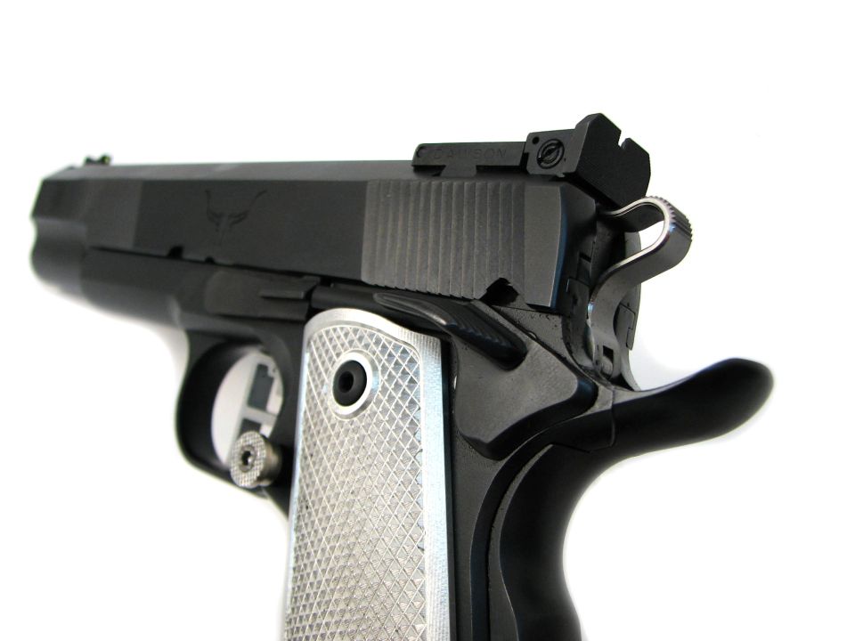 Close-up of a black 9mm handgun with silver checkered grips