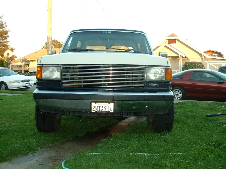 White and dark blue Ford Bronco front view, chrome grille, California license plate 2HTA914