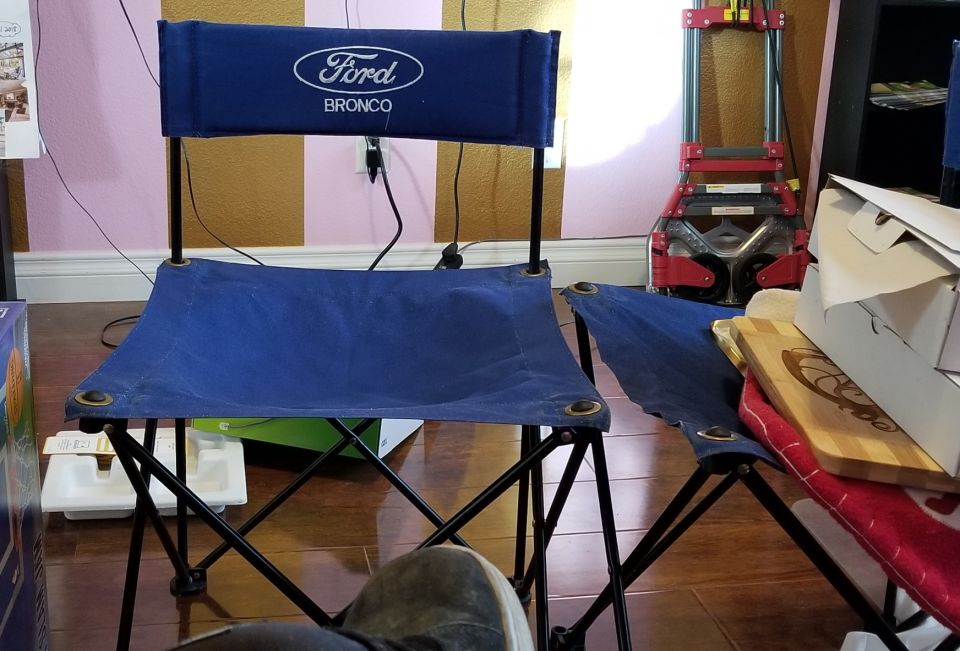 Blue folding chairs with Ford Bronco logo on backrest. A red dolly is in the background