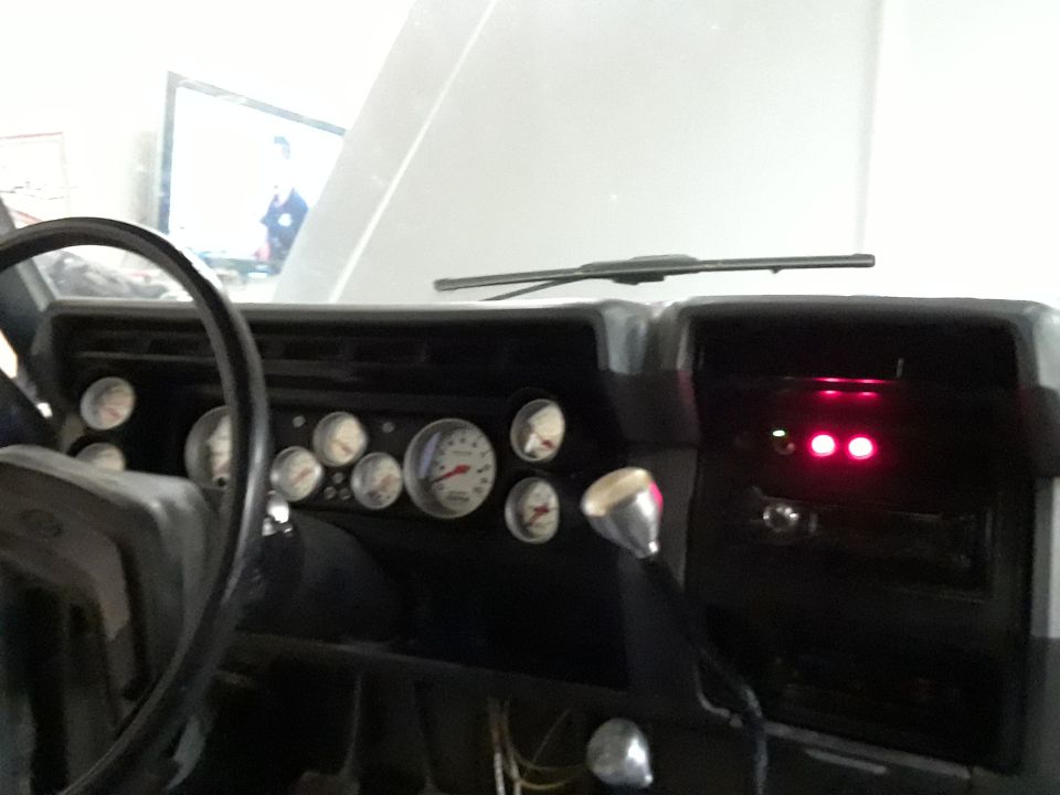 Dashboard interior with multiple gauges and a chrome shifter. Two red indicator lights are illuminated