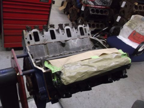 1964 Ford Galaxie - Engine block on a stand, partially covered with paper and tape, in a workshop setting.