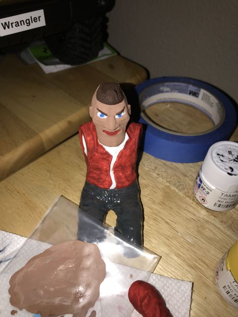 1989 Ford Bronco - A figurine with a mohawk hairstyle and a red vest is placed on a table next to art supplies.