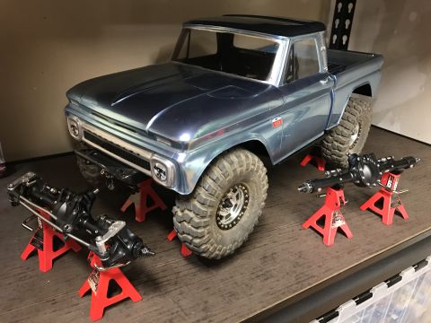 1989 Ford Bronco - A model truck is displayed on jack stands with additional axles nearby.
