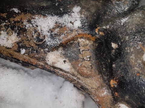 1995 Ford F-150 - Rusted metal part with partial text 'L4' visible, partially covered in snow.