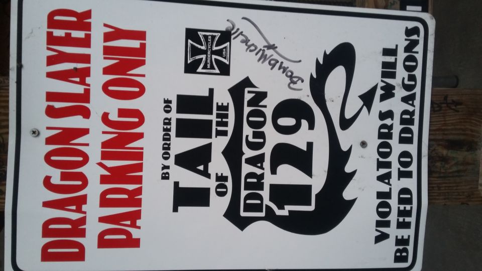 Sign reads 'DRAGON SLAYER PARKING ONLY' and 'BY ORDER OF THE TAIL OF THE DRAGON 129' and 'VIOLATORS WILL BE FED TO DRAGONS'