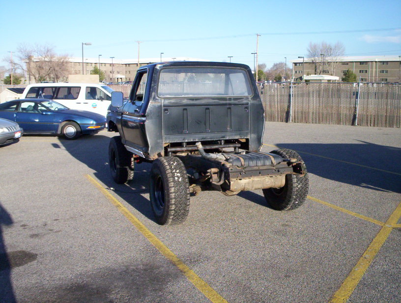 Black pickup truck chassis, rear view. Other cars visible