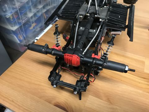 1989 Ford Bronco - Close-up view of the suspension and drivetrain of a remote-controlled car chassis, red and black components.