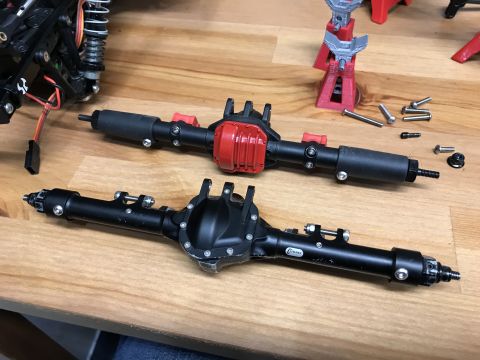 1989 Ford Bronco - Two RC car axles are laid out on a table, with parts and tools nearby.