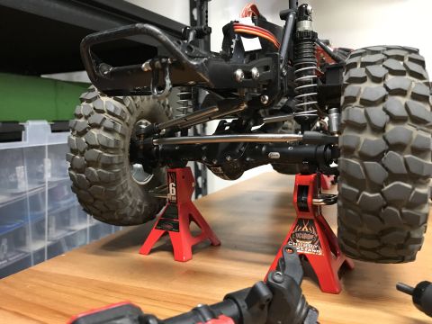 1989 Ford Bronco - Close-up of an RC car's undercarriage, supported by jack stands, revealing its mechanical components.