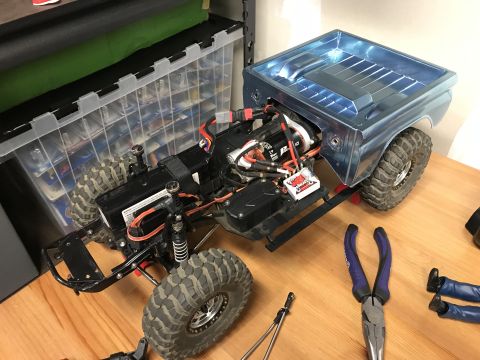 1989 Ford Bronco - RC truck chassis with body and electronics visible, sitting on a wooden surface.