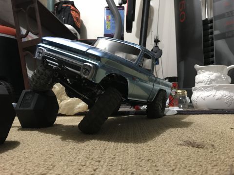 1989 Ford Bronco - A remote-controlled pickup truck is positioned on a carpeted surface with one wheel elevated on a weight.