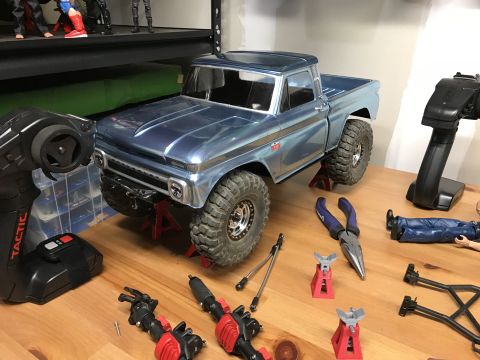 1989 Ford Bronco - A model pickup truck is being worked on, surrounded by RC equipment and tools.