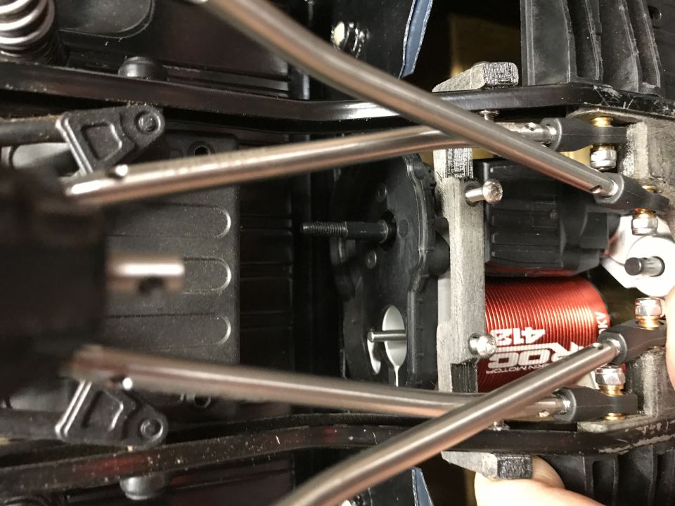 Close-up of RC car drivetrain showing motor, gears, and suspension components