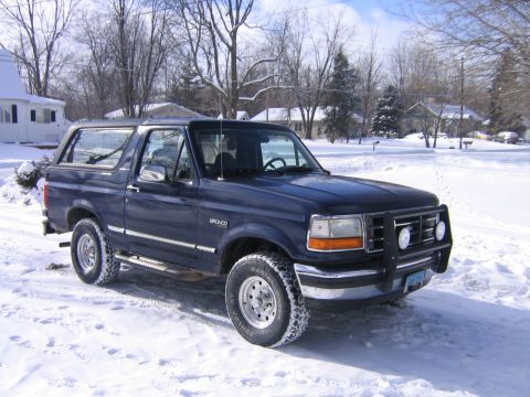 1994 Ford Bronco - A dark blue Ford Bronco sits in a snowy landscape, its brush guard visible.