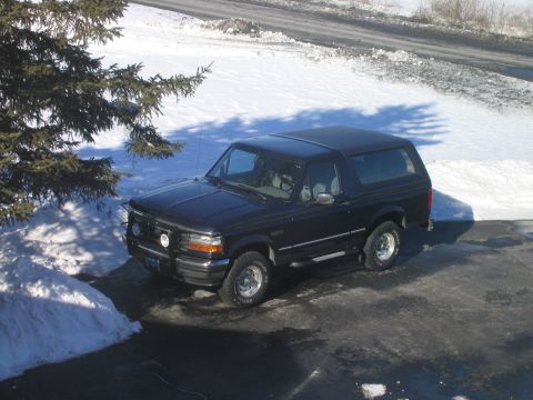 1994 Ford Bronco - This 1994 Ford Bronco is seen in a snowy environment, parked on a dark asphalt surface.
