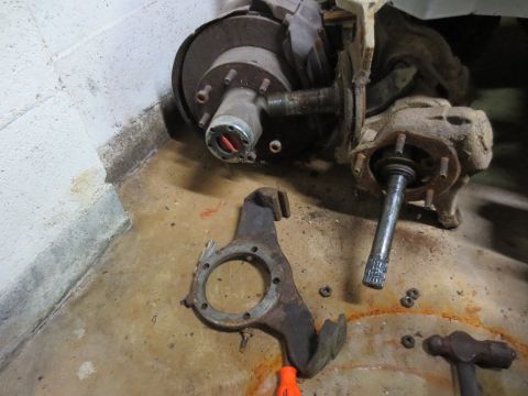 1967 Ford F-250 - Disassembled front axle components, including a hub with a red locking mechanism, are laid out on a concrete floor.