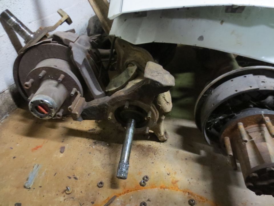 pile of rusty truck suspension components including hubs, brake drums, and spindles