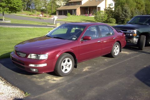 1996 Nissan Maxima - A maroon 1997 Nissan Maxima is parked next to a dark SUV on a paved surface.