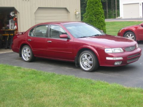1996 Nissan Maxima - A red 1996 Nissan Maxima sedan is parked in front of a garage.