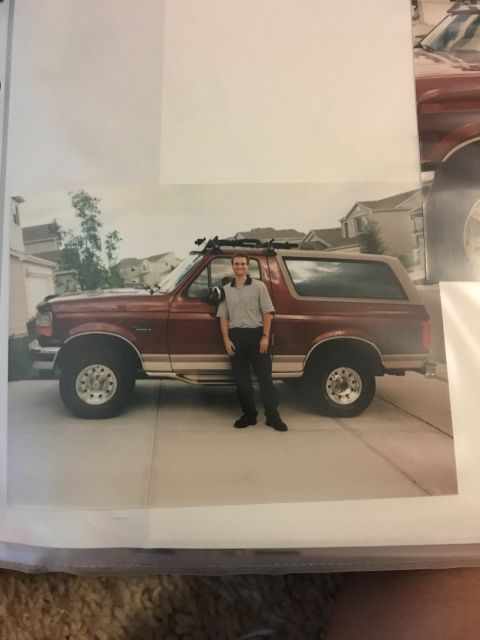 1996 Ford Bronco - A man stands next to a red 1996 Ford Bronco parked in a driveway.