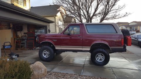 1996 Ford Bronco - This lifted Ford Bronco is parked in a suburban driveway next to a garage.