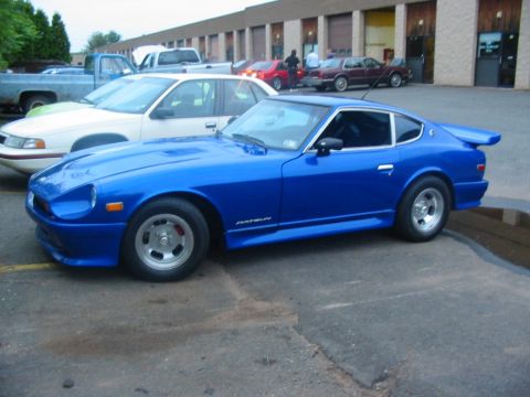 1994 Ford Bronco - Blue Datsun 280Z with aftermarket wheels and spoiler parked in a lot.