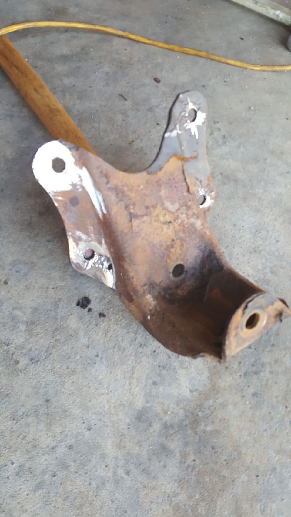 Rusted metal suspension part with white paint markings