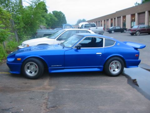 1994 Ford Bronco - A blue Datsun sports car is parked in a lot with other vehicles visible.