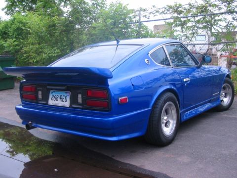 1994 Ford Bronco - A blue sports car is parked on a wet surface, showing its rear end and spoiler.