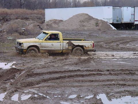 1994 Ford Bronco - Pickup truck struggling through deep mud, driver visible inside the cab.