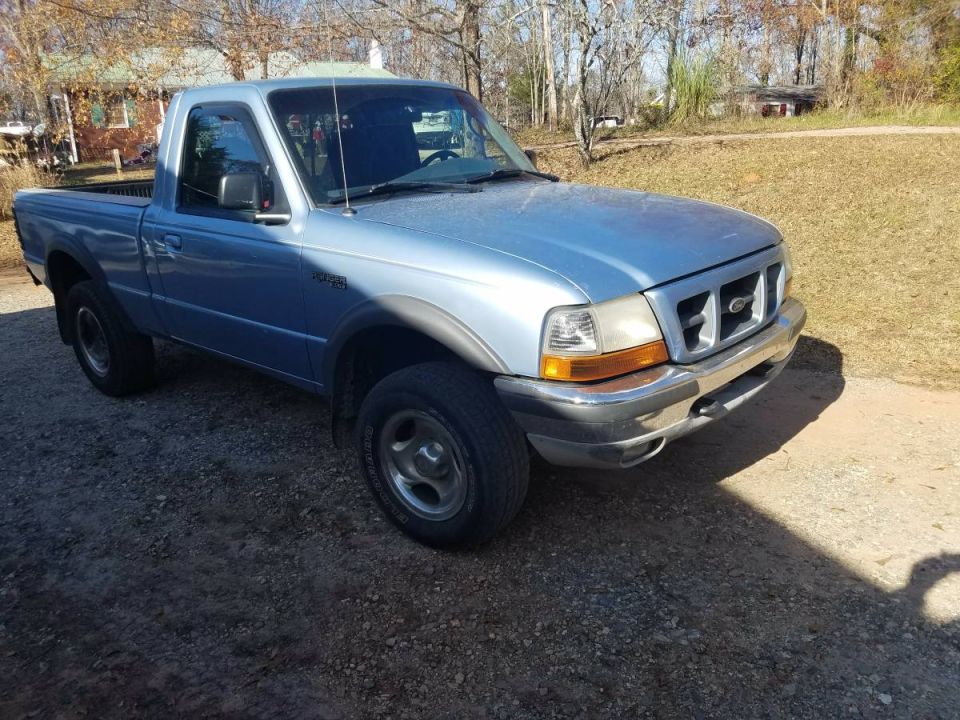1998 Ford Ranger pickup truck, light blue, parked on gravel.