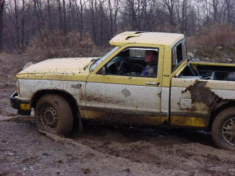 1994 Ford Bronco - Pickup truck stuck in mud, with visible damage to the rear quarter panel.