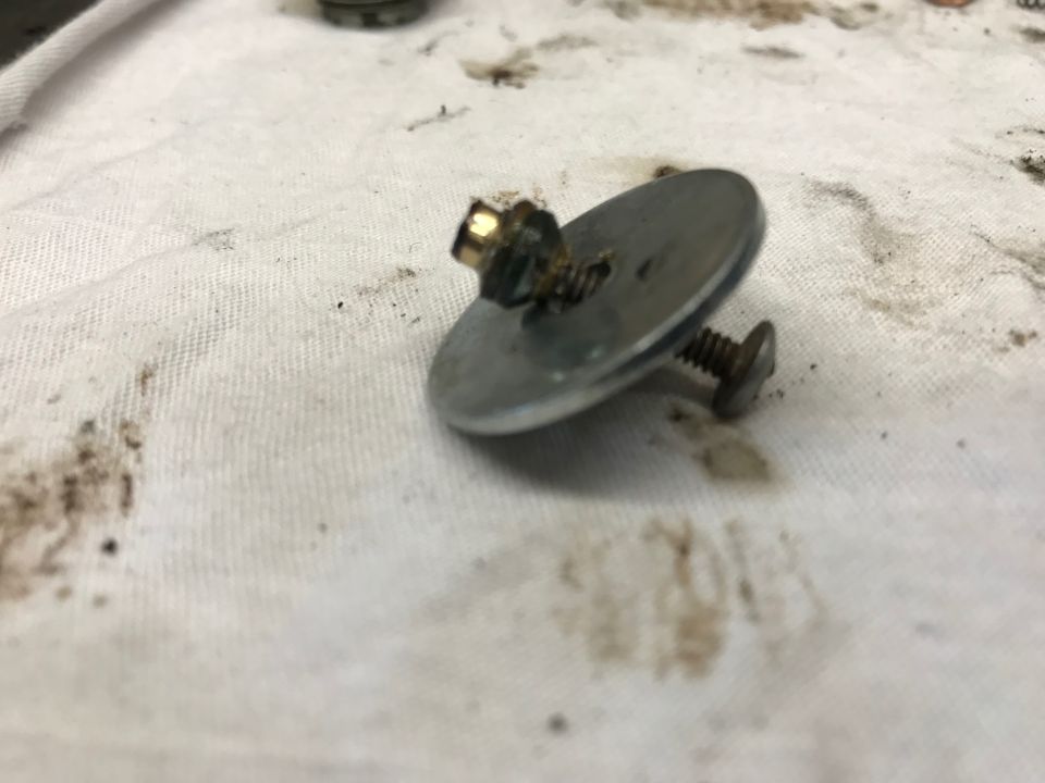 Close-up of a metal washer with bolt and nut on a stained white cloth.