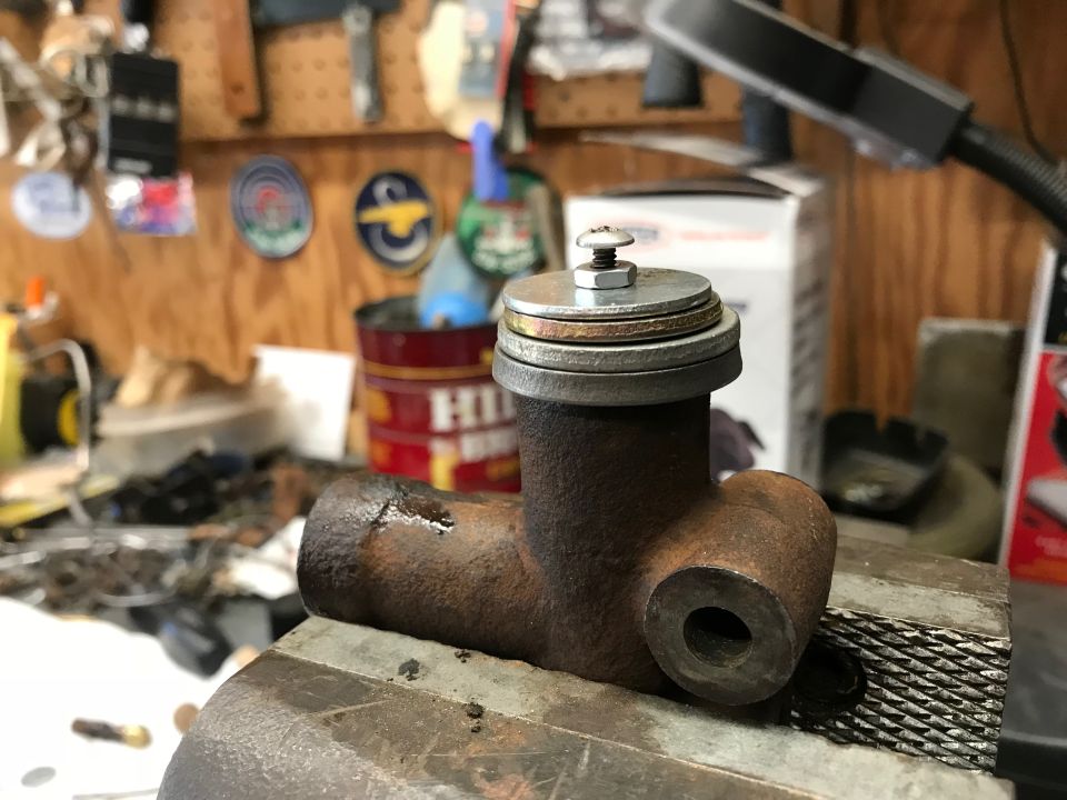 Rusty cast iron brake master cylinder part in a vise.