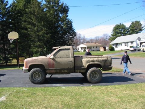1994 Ford Bronco - A dirty pickup truck sits on a driveway with two people visible in the scene.