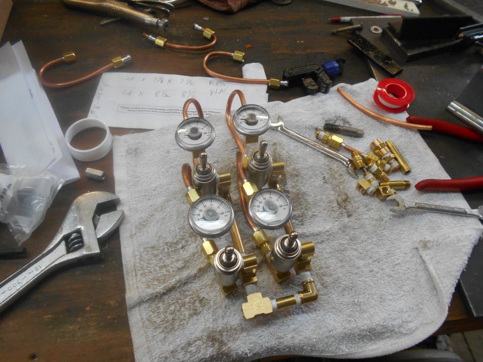 Plumbing components with gauges, copper tubing, and brass fittings on a workbench.