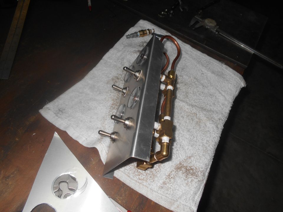 Custom control panel with toggle switches and brass plumbing on a towel.