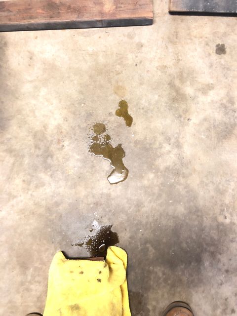 1996 Ford Bronco - A yellow rag is used to clean up an oil spill on a concrete floor, with the Supermotors.net logo visible in the corner.