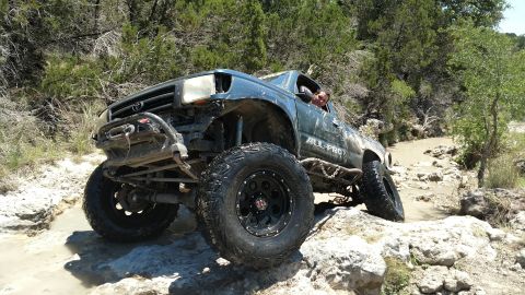 1989 Ford Bronco - This modified Toyota Tacoma navigates a rocky off-road course with its front-left tire significantly elevated.