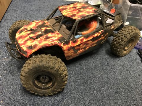 1989 Ford Bronco - Remote control rock crawler with a flame graphic body sits on a carpeted surface.