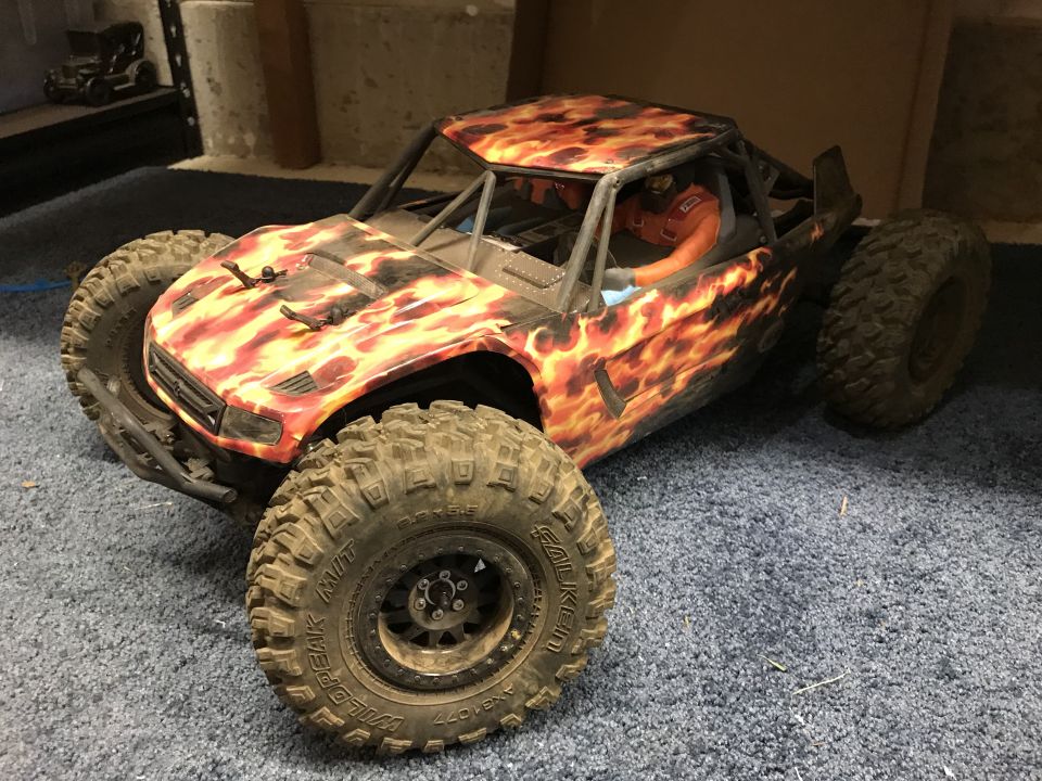 RC rock crawler with flame graphics on hood and sides, large off-road tires