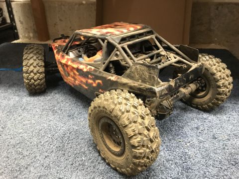 1989 Ford Bronco - A remote control rock crawler with flame graphics and large tires sits on a carpeted surface.