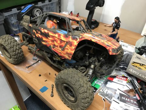 1989 Ford Bronco - A remote control rock crawler with flame graphics sits on a workbench surrounded by tools and parts.