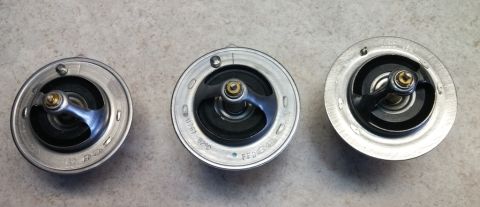 2008 Hyundai Accent - Three engine thermostats are displayed on a concrete surface, with text visible on the middle unit.